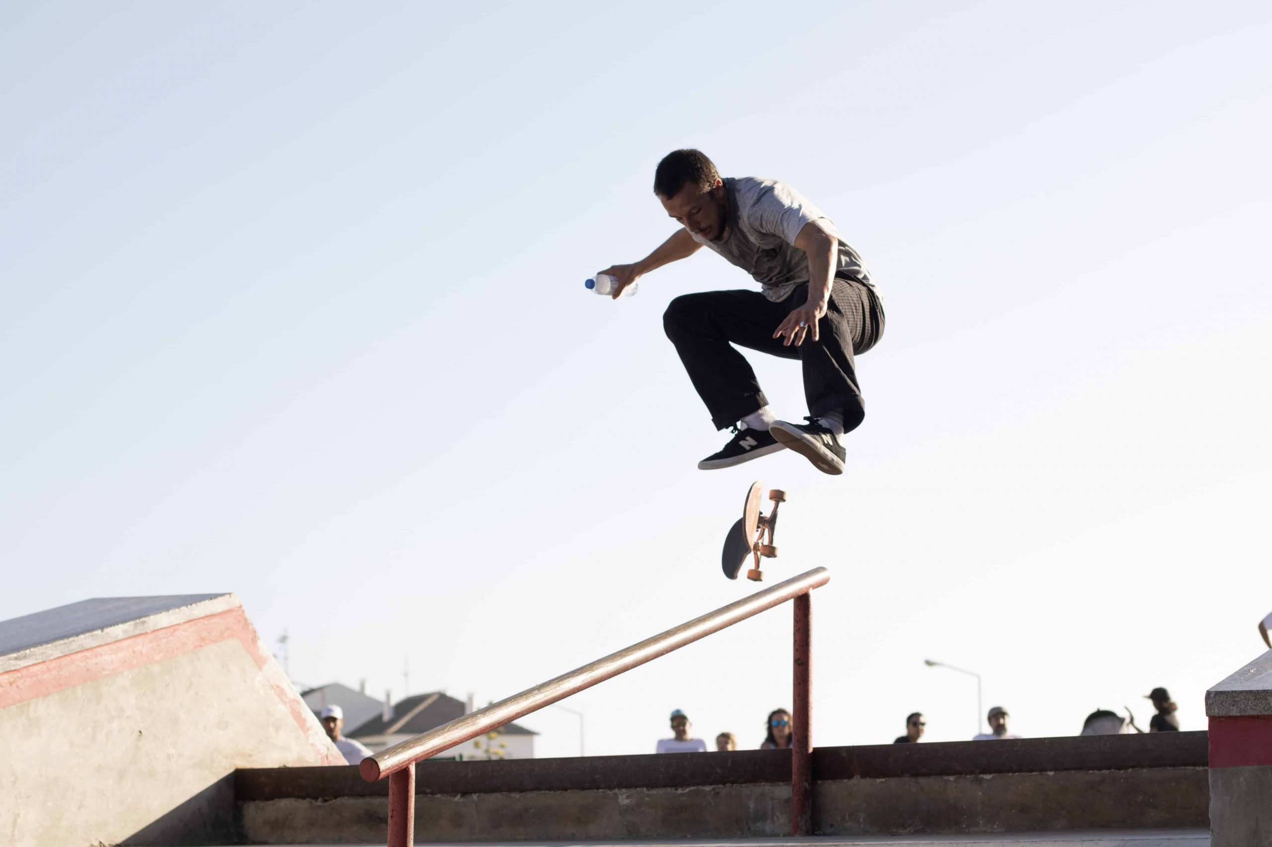 man wearing white t shirt performing skateboard tricks on rail under blue sky stockpack pexels scaled